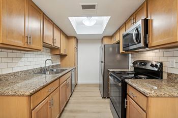 A kitchen with wooden cabinets and granite countertops. at The Viridian Apartments, Scottsdale, Arizona